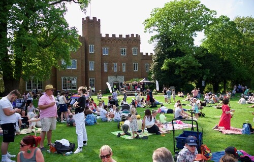 People sitting on the main lawn at Hertford Castle.