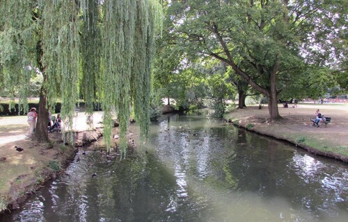 The River Lea with people feeding the ducks on both sides of the bank. 